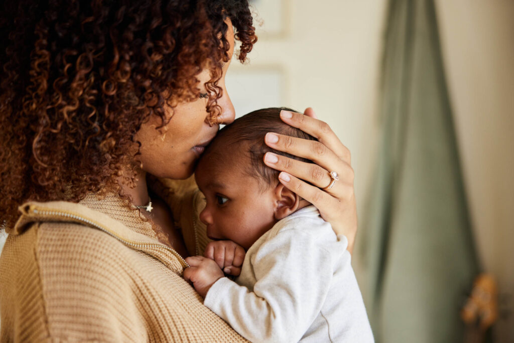 mother kissing infant